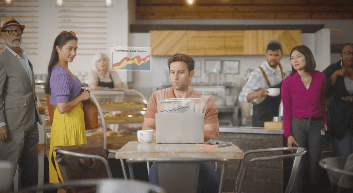 Legal professional security tips: Man with laptop in coffee shop with people looking at his screen. Credit - 3M